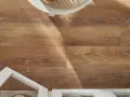 Drewnopodobne panele laminowane czy winylowe tworzą ciepłą podłogę. Widać fragment białej szafki i okrągłego stolika.