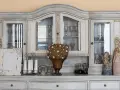 Witryna w kolorze dąb bielony, z przeszklonymi drzwiczkami, kieliszkami, figurkami aniołów i ozdobną kulą.