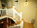 Elegancka klatka schodowa w stylu angielskim z białymi balustradami i drewnianymi elementami.