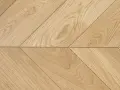 Drewniana podłoga ułożona we wzór francuska jodełka. Jasne deski tworzą elegancki, ukośny wzór.
