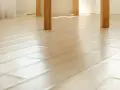 Jasna podłoga z drewna, gdzie wybrzuszone panele na łączeniach tworzą subtelny wzór.