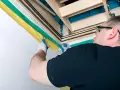 Mężczyzna w rękawiczkach montuje izolację schodów strychowych.