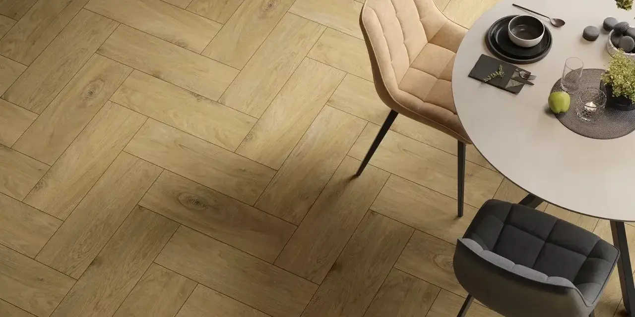 Eleganckie wnętrze z podłogą w jodełkę. Okrągły stół z krzesłami, nakryty do posiłku.