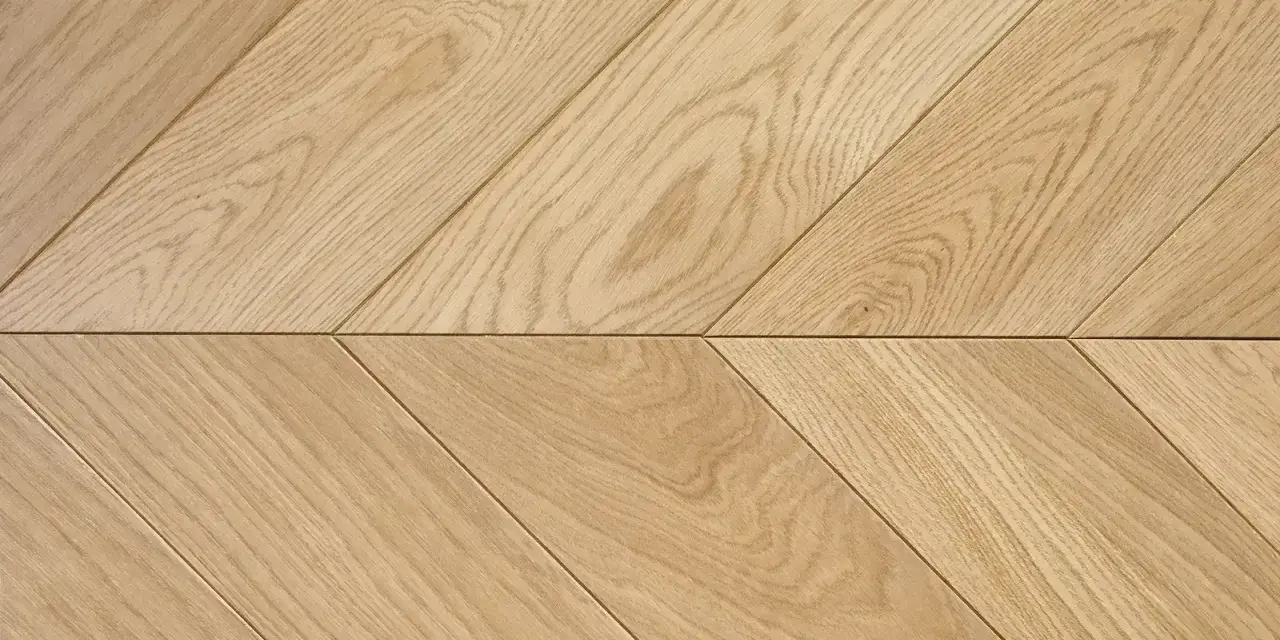 Drewniana podłoga ułożona we wzór francuska jodełka. Jasne deski tworzą elegancki, ukośny wzór.