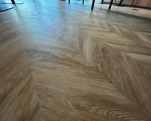 Drewniane panele ułożone we wzór jodełki. Jaki podkład zastosowano pod panele?