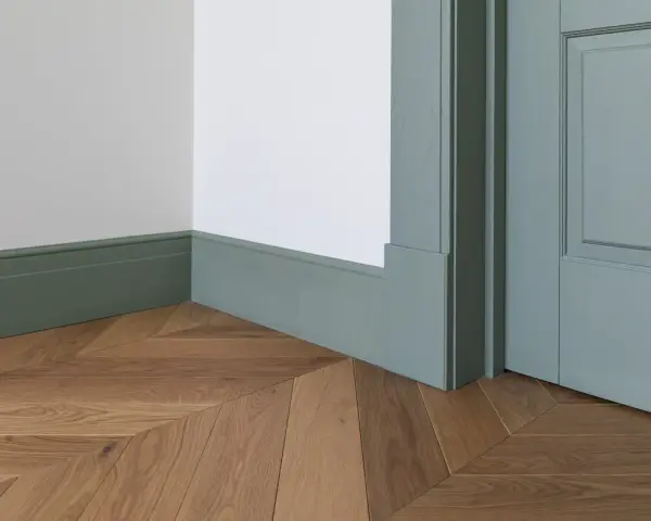 Elegancka listwa przypodłogowa w kolorze miętowym, z widocznymi wymiarami, idealnie komponuje się z drewnianą podłogą ułożoną we wzór jodełki.