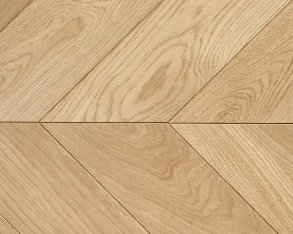 Drewniana podłoga ułożona we wzór francuska jodełka. Jasne deski tworzą elegancki, ukośny wzór.