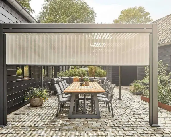 Zasłona przeciwsłoneczna nad stołem i sofą na tarasie. Świetny pomysł, czym zabudować boki tarasu, by stworzyć przytulną przestrzeń.