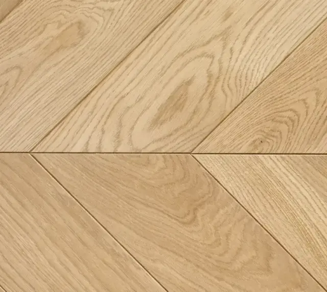 Drewniana podłoga ułożona we wzór francuska jodełka. Jasne deski tworzą elegancki, ukośny wzór.